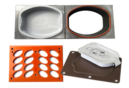 United Silicone custom heat seal tooling (clockwise from top left): rigid packaging silicone bonded support or part holding fixture with a preformed plastic tray in place, the same support fixture with the plastic tray removed, a silicone seal head and a silicone covered nest or support structure.