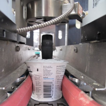 A typical yogurt cup undergoing leak testing  after lidding heat sealing. This photo is of a Teledyne TapTone yogurt cup leak  tester in operation.